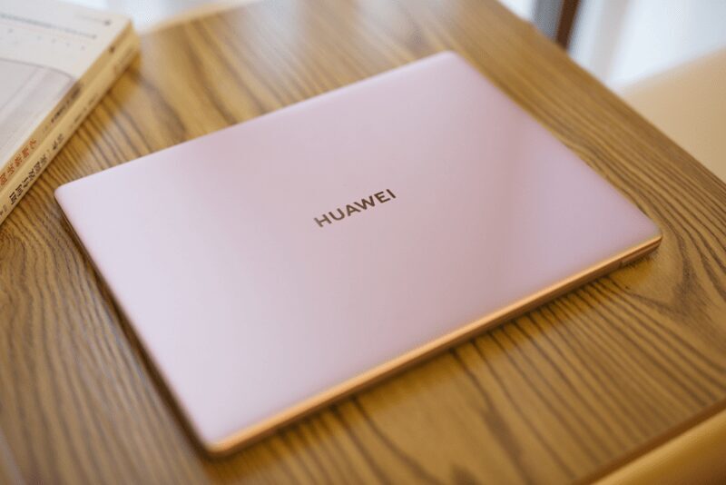 Розовый ноутбук Huawei MateBook X лежит на деревянном столе