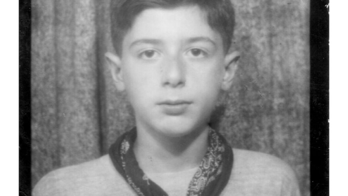 Черно-белое фото мальчика с короткими волосами и повязкой на шее на фоне занавески