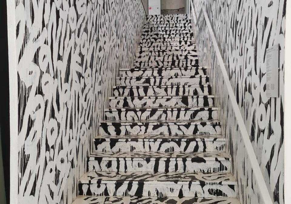 Восхождение по лестнице с черно-белым зебра-коридором