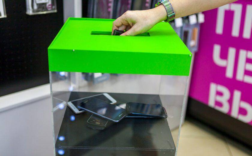 Tele2 принимает на переработку телефоны в салонах Москвы и области 7 Человек вставляет телефон в автомат для переработки телефонов