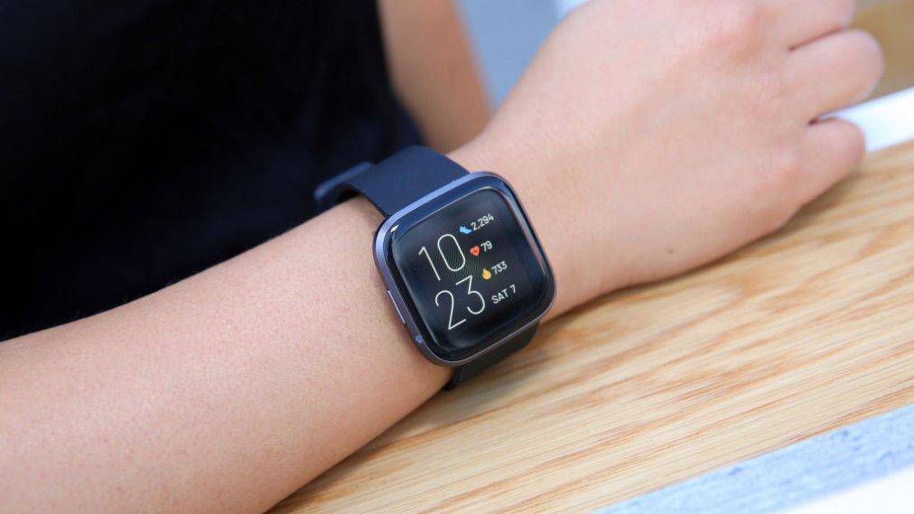 Умные часы Google Fitbit на руке человека показывают время и данные о здоровье