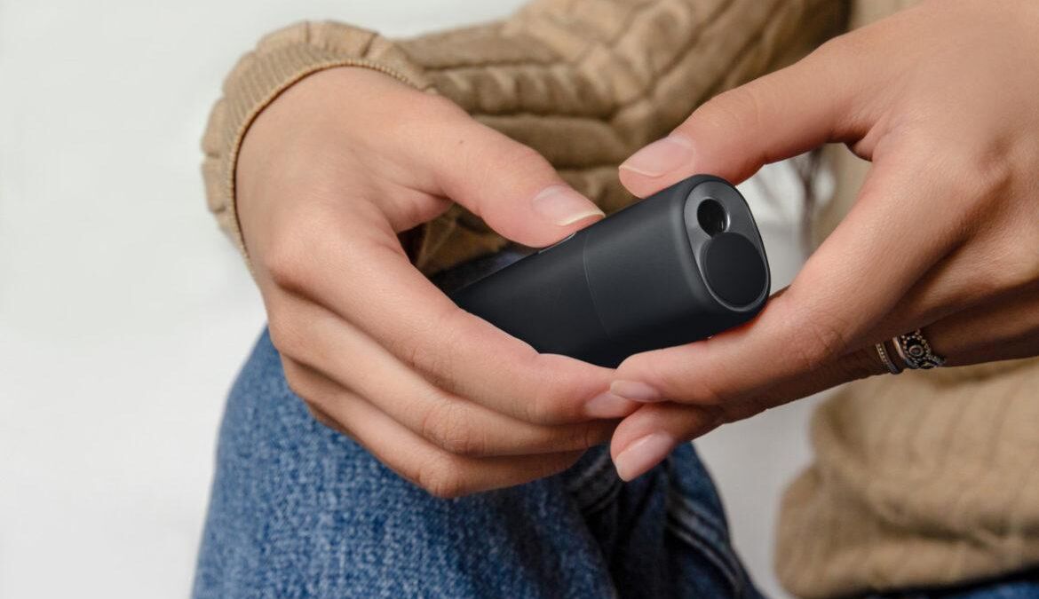 Рука держит устройство IQOS lil SOLID в руке