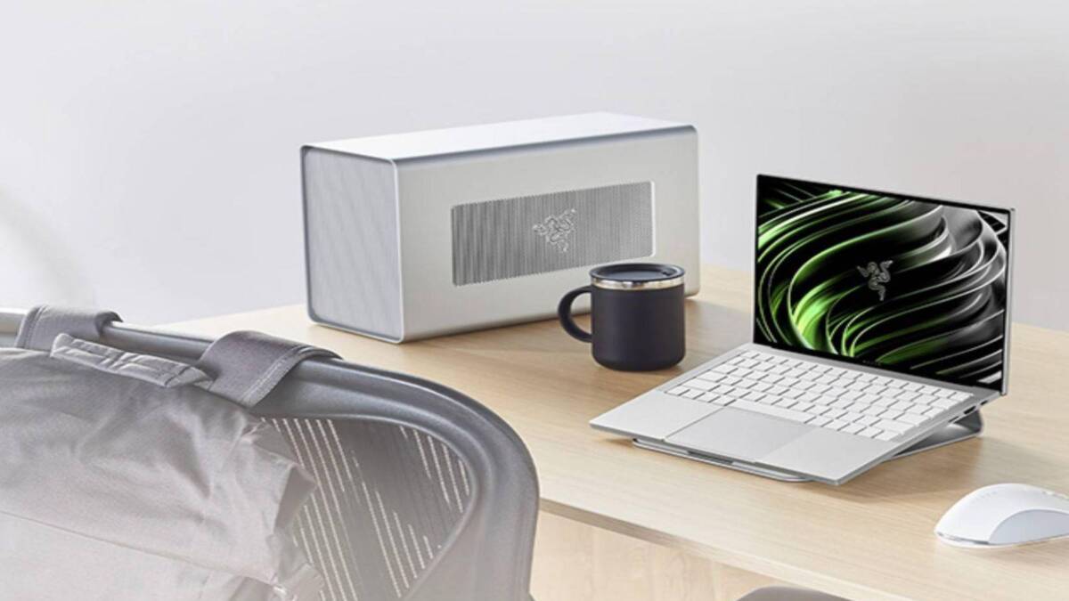 белый ноутбук Razer Book 13 с черной клавиатурой и дисплеем, раскрытым на рабочем столе