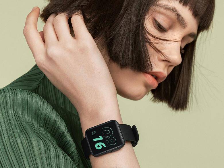 Женщина с черной стрижкой смотрит на умные часы Redmi Watch