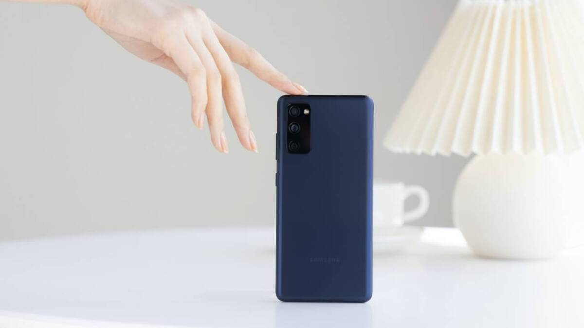 Проблемы с сенсорным экраном Galaxy S20 FE остались и после трех обновлений 3 Рука приближается к синим смартфоном Samsung Galaxy S20 FE на белом столе