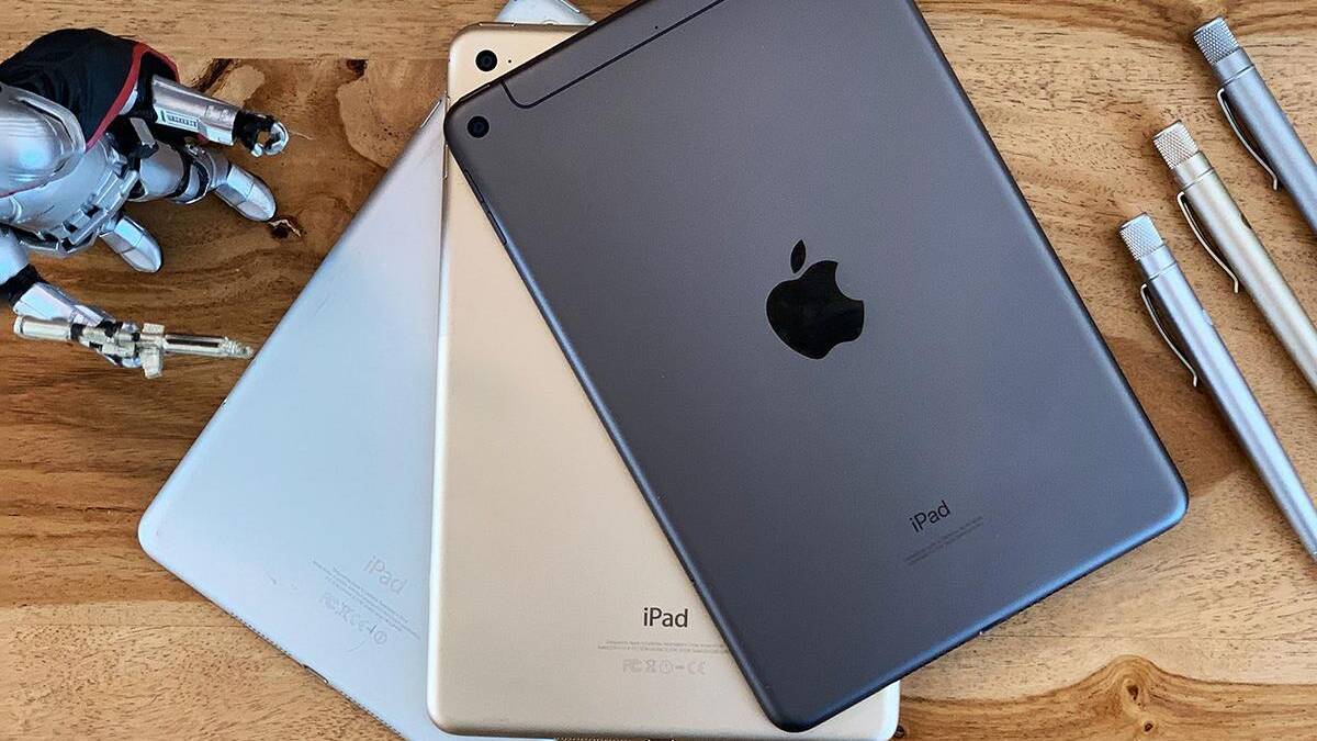 Три iPad на деревянном столе рядом с тремя серебряными ручками