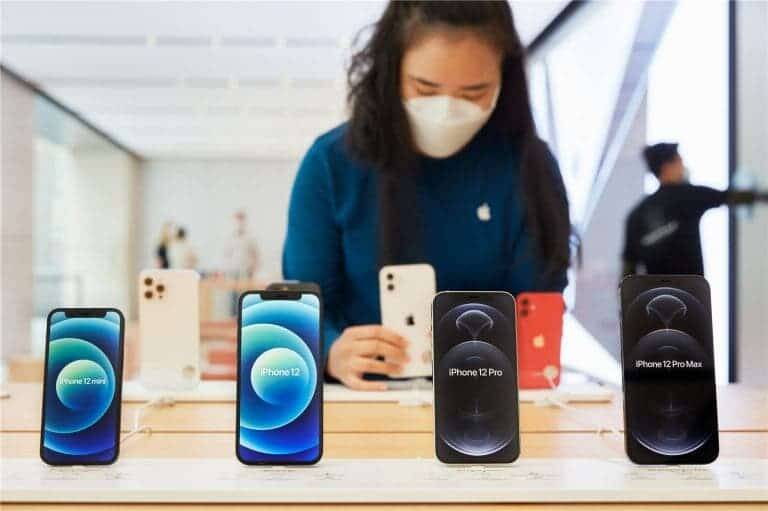 Смартфоны Huawei Mate 40 и iPhone 12 закончились в Китае 3 Женщина в маске рассматривает дисплеи iPhone 12 и iPhone 12 Pro Max
