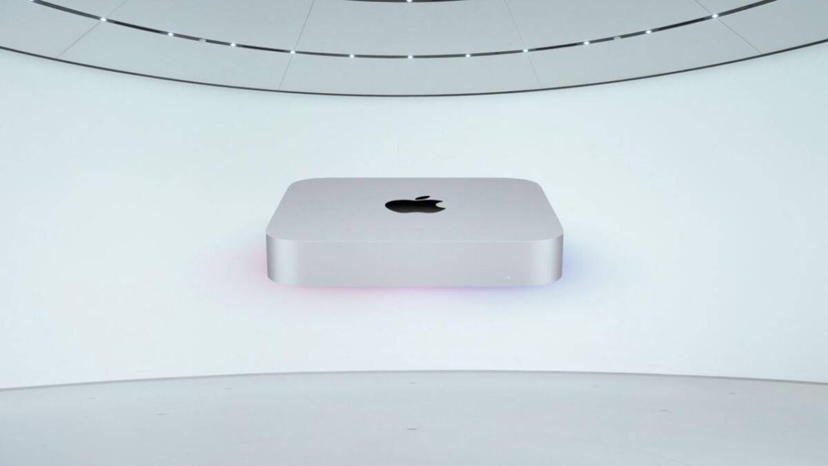 Новый Mac mini на фоне светлого стенда с черным логотипом Apple