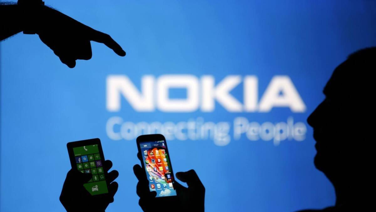 Силуэты людей, держащих смартфоны Nokia с яркими экранами фоном логотип Nokia