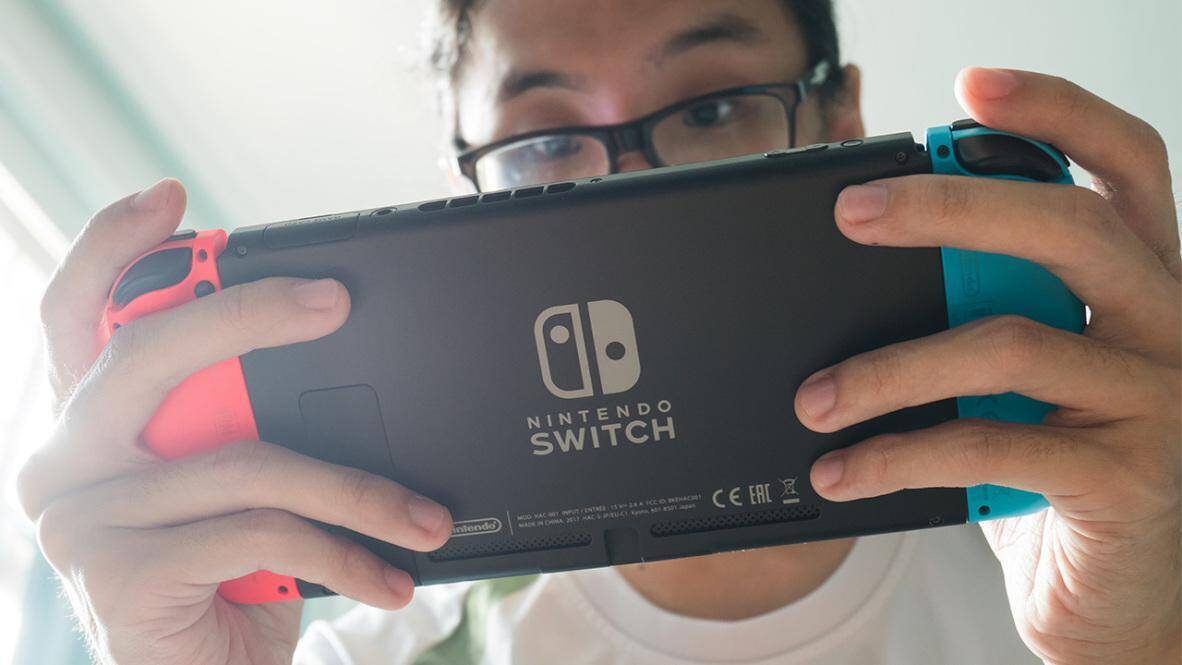 Пользователь держит Nintendo Switch со стороны задней панели