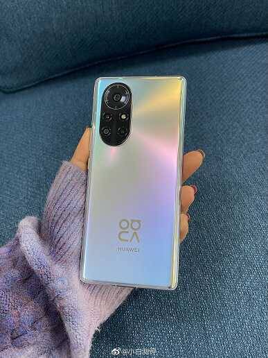 Мужчина с длинными темными волосами держит смартфон realme GT 8 Pro