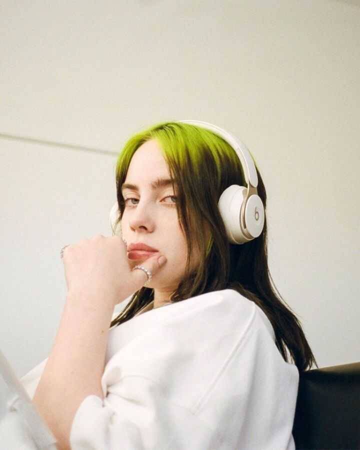 Девушка с черными и зелеными волосами в наушниках Beats и белой одежде