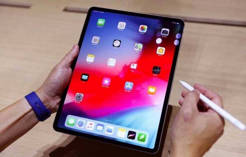 Планшет Apple iPad с интерфейсом и стилусом в руке