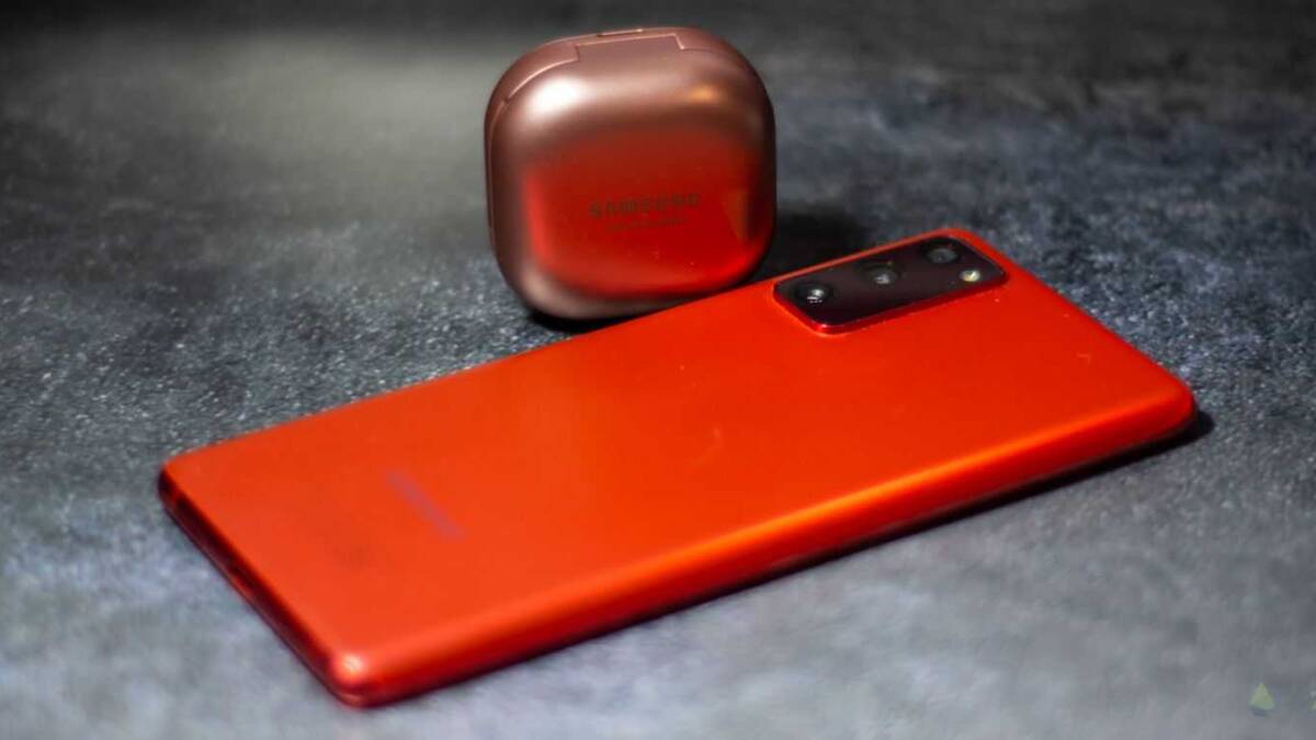 Красный сотовый телефон Samsung Galaxy Note на черной поверхности с наушниками Galaxy Buds Pro в футляре