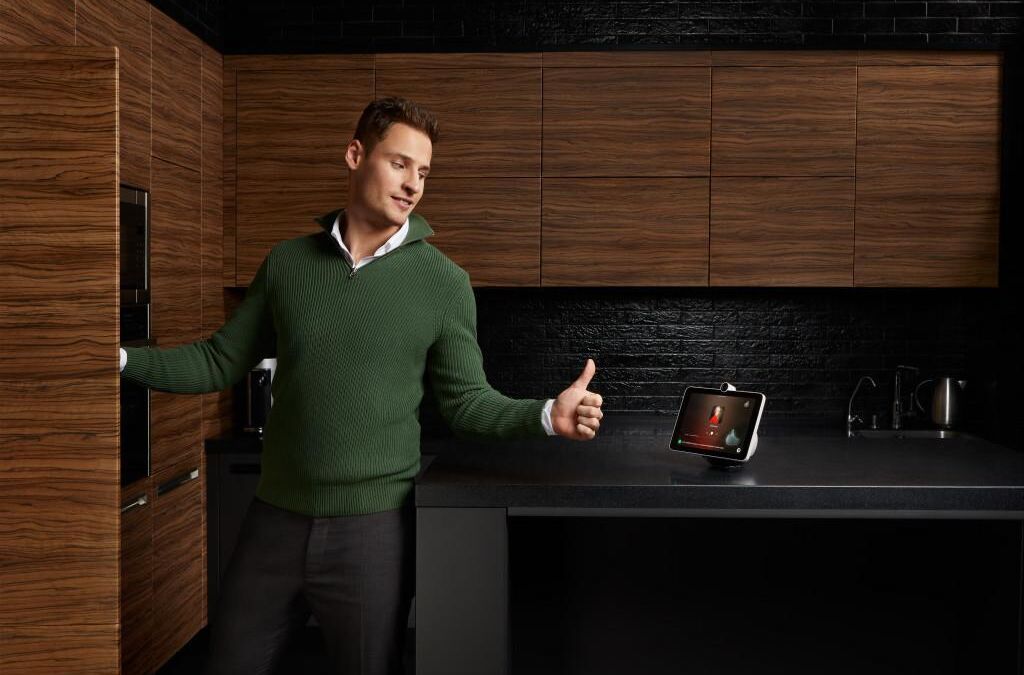 Мужчина с зеленым свитером показывает умный экран SberPortal на кухне