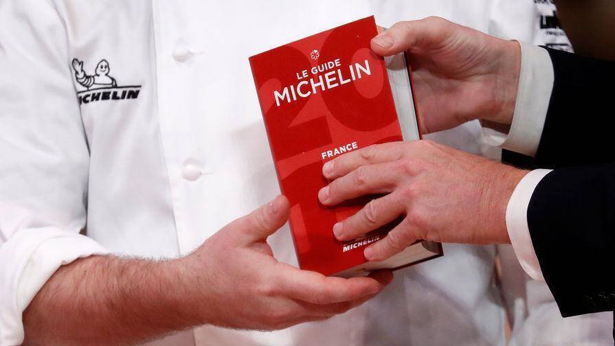 Рука держит обложку руководства MICHELIN Франция — гид для ресторанов и отелей