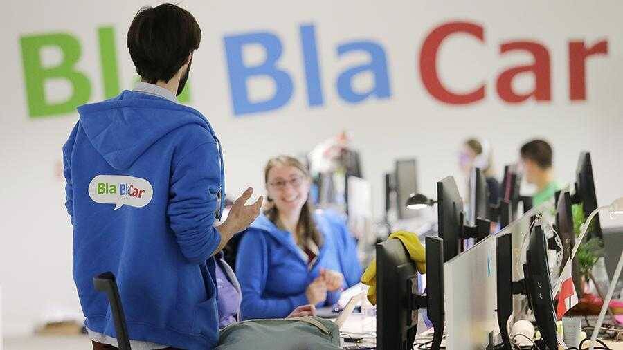 Работник BlaBlaCar в синим худи объясняет что-то клиенту в офисе