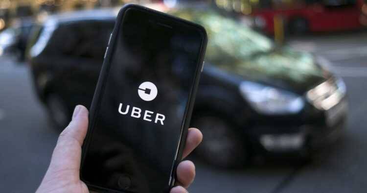 Рука держит смартфон с логотипом Uber на экране