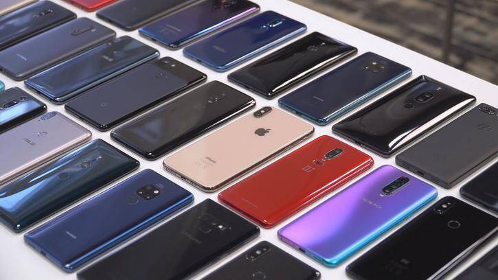 Различные модели смартфонов на белом столе сзади камеры изогнутых экранов