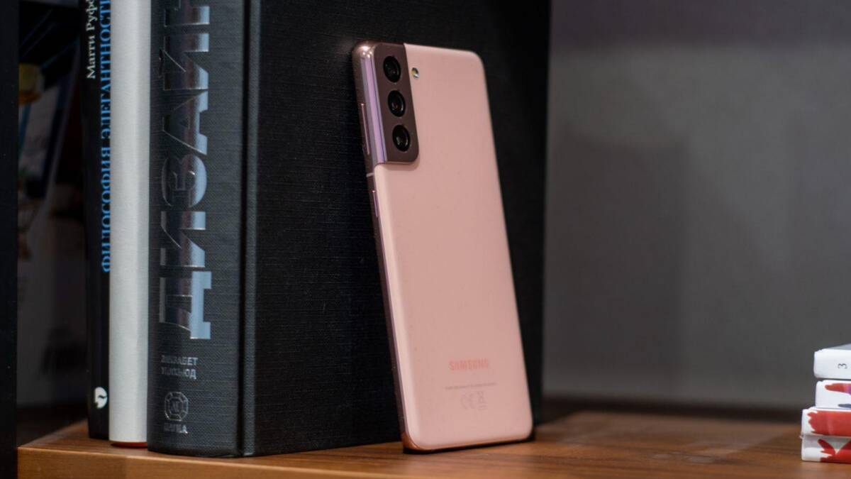 Розовый смартфон Samsung Galaxy S21 Ultra стоит на полке рядом с книгами