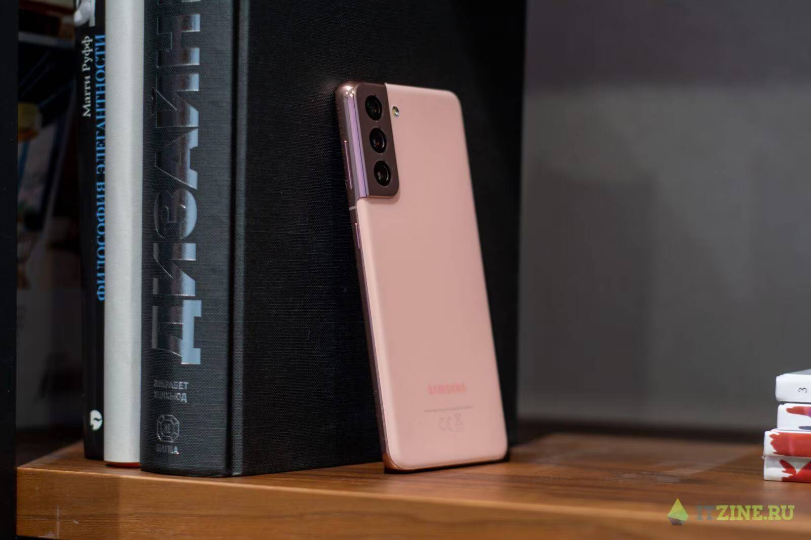 Розовый смартфон Samsung Galaxy S21 Ultra стоит на полке рядом с книгами