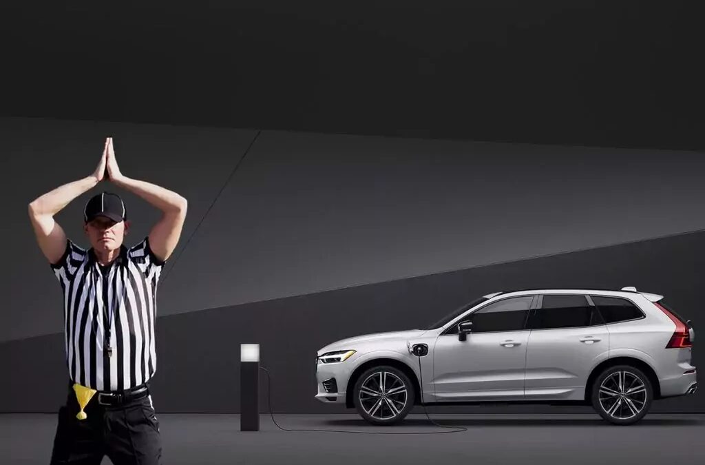 Рефери с поднятыми руками в спортивной форме у электромобиля Volvo XC60 подключенного к зарядной станции