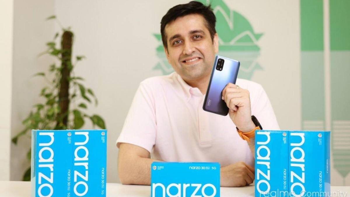 Мужчина держит смартфон Narzo 30 Pro на столе