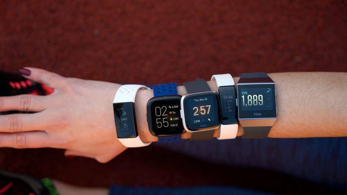 Несколько умных часов Fitbit на руке с интерфейсами и шагомером в магазине Google