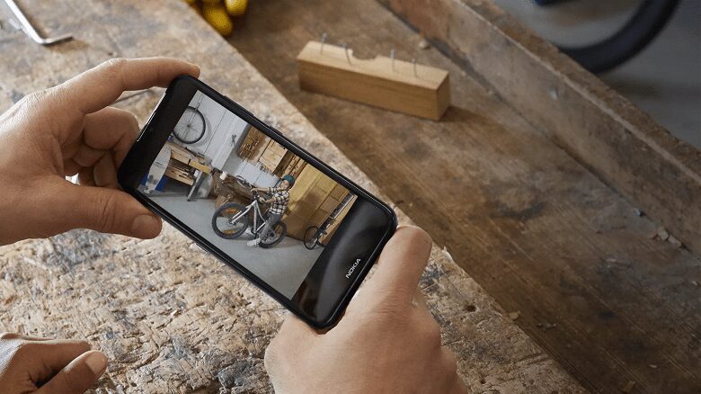 HMD Global представила бюджетный смартфон Nokia 1.4 4 Человек фотографирует велосипед с помощью смартфона Nokia 1.4 в мастерской