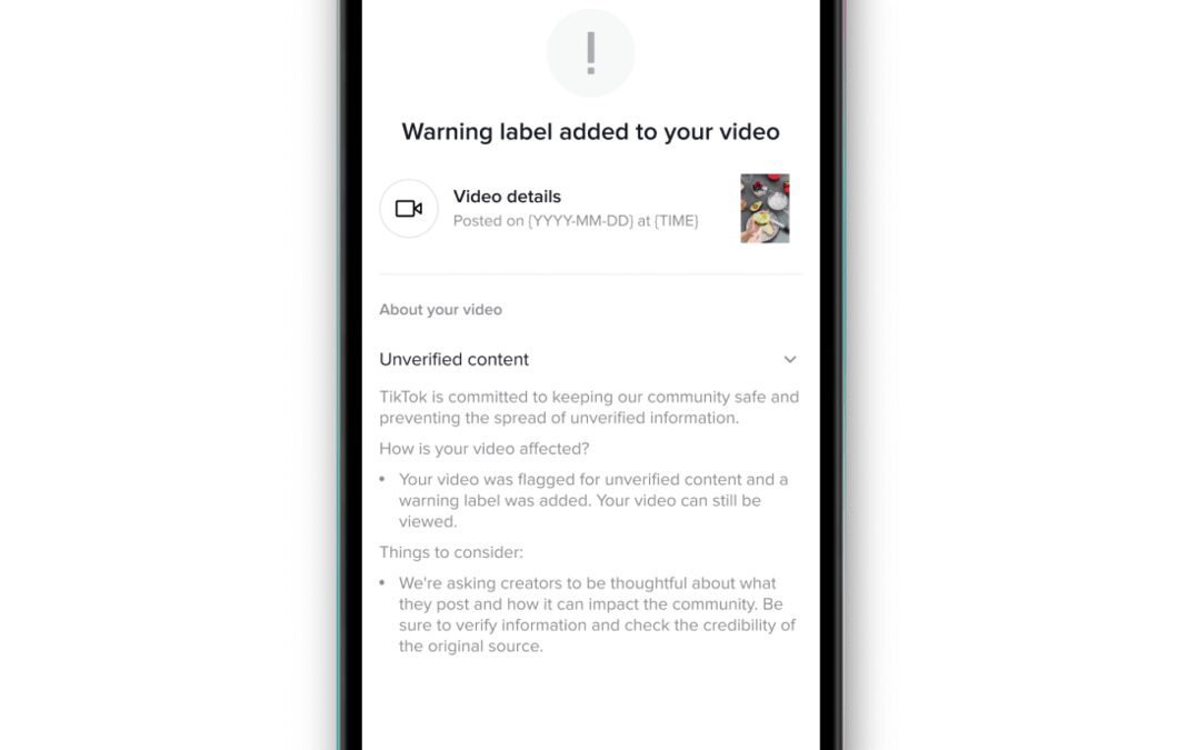 Экран смартфона отображает уведомление о добавлении предупреждающей метки к видео в TikTok
