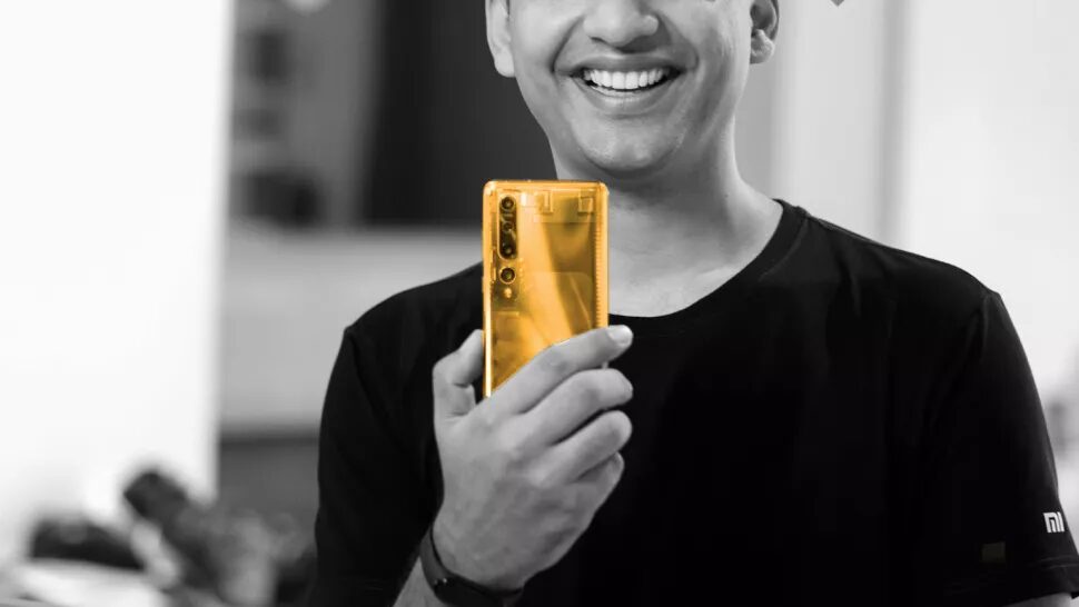 Человек с smiling держит золотой смартфон Xiaomi на переднем плане