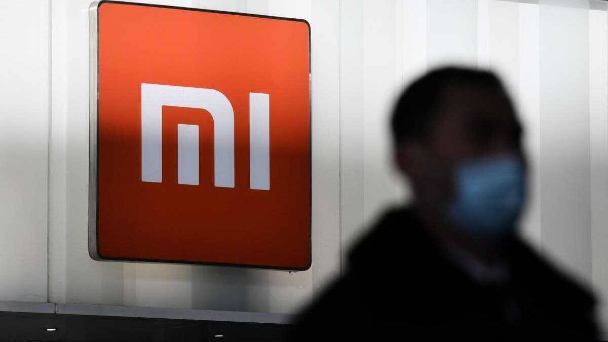 Значок Xiaomi на стенде с человеком в маске рядом