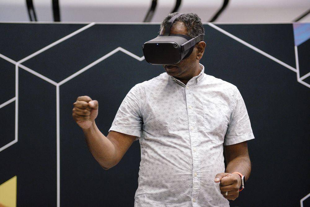 Человек с VR-гарнитурой Apple в руке демонстрирует победу