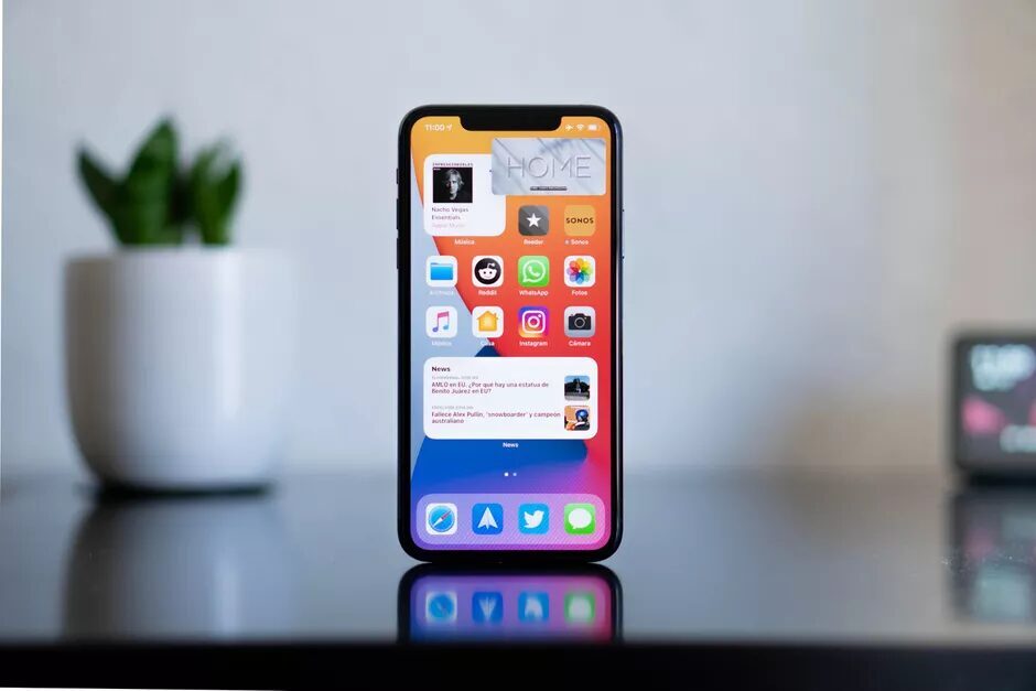 Роскошный смартфон Apple iPhone на гладком столе рядом с лампой и растением