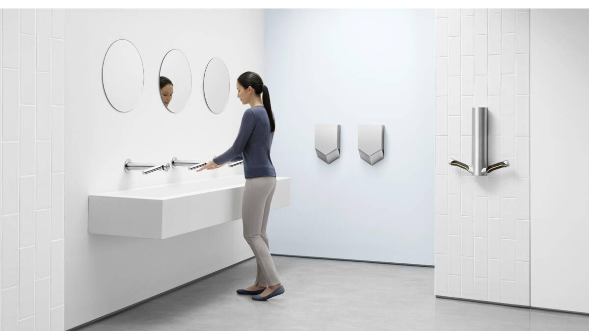 Женщина моет руки в раковине Dyson Airblade в санузле