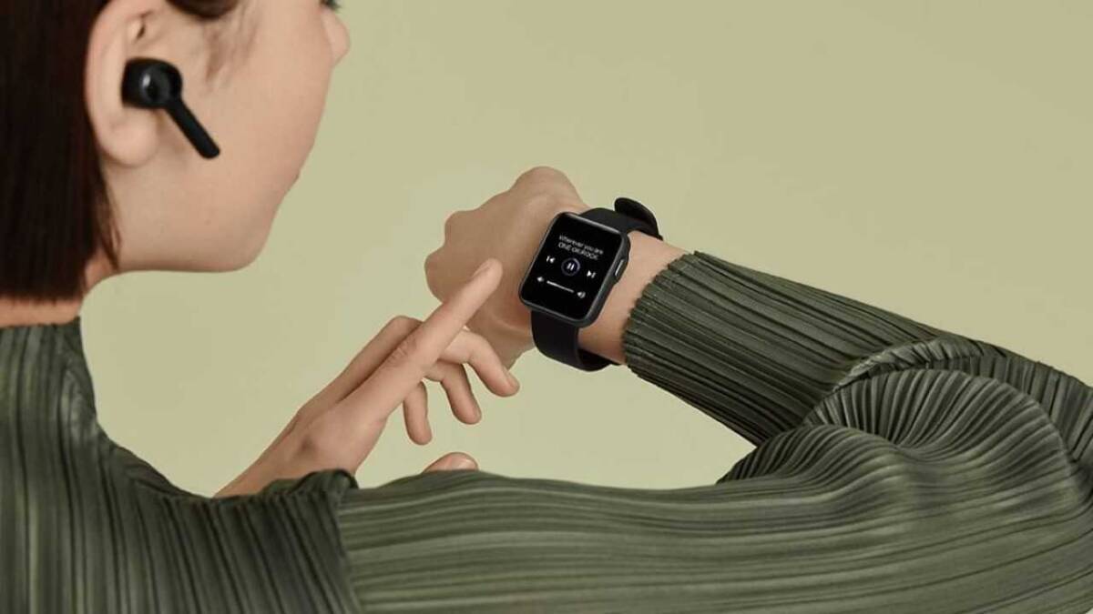 Женщина использует умные часы Xiaomi Mi Watch Lite с интерфейсом воспроизведения музыки