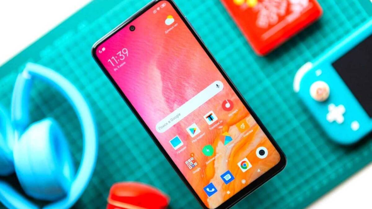 Смартфон Xiaomi на фоне зеленой поверхности и аксессуары
