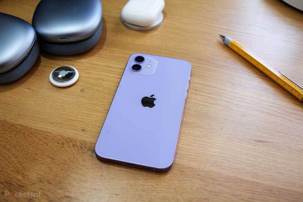 Фиолетовый iPhone 12 на деревянной поверхности с аксессуарами