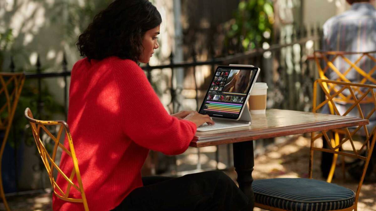 Женщина использует iPad Pro на улице на деревянной скамейке