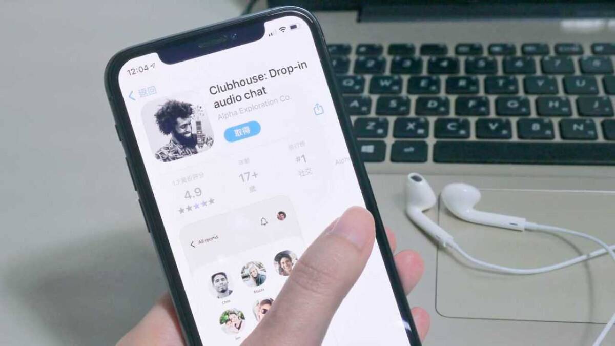 Экран смартфона с приложением Clubhouse и наушники на столе