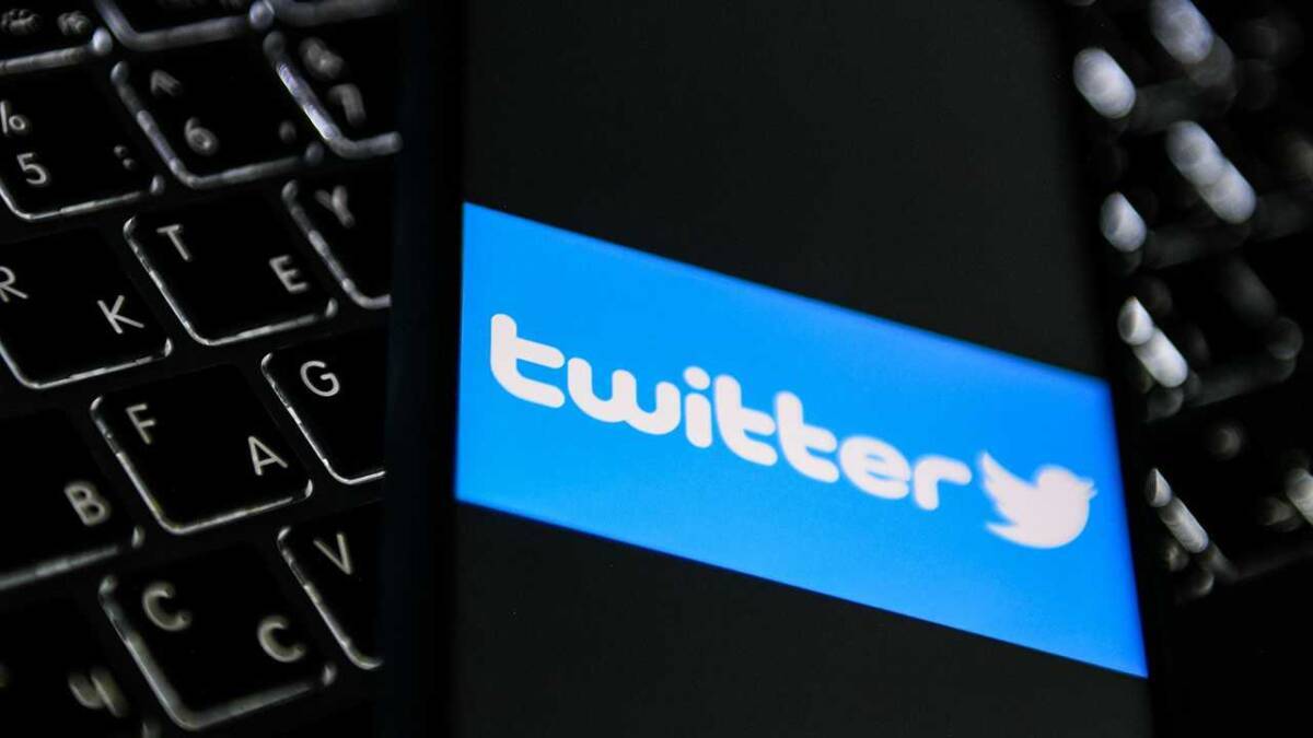 Экран смартфона с логотипом Twitter и клавиатурой ноутбука