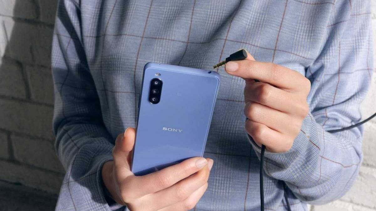 Человек держит смартфон Sony Xperia 10 III с кабелем в руке
