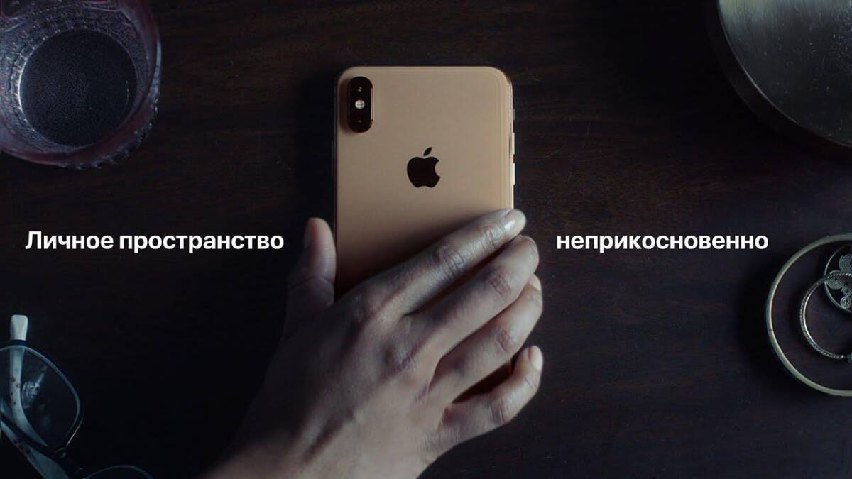 Руки с часами и браслетами держат iPhone на рабочем столе, аксессуары рядом