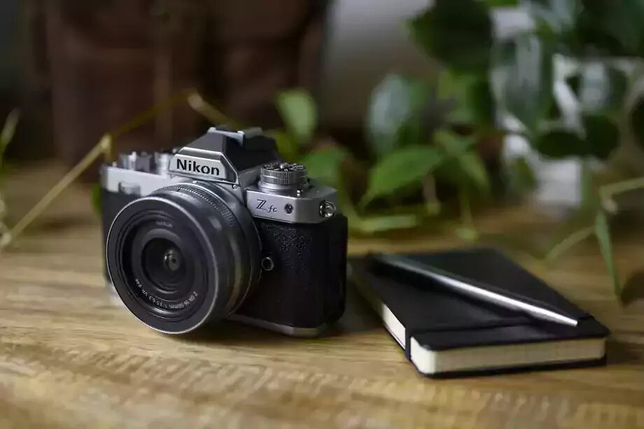 Зеркальный фотоаппарат Nikon Z FC с объективом на деревянном столе
