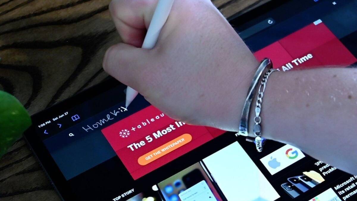 Пальцем держит Apple Pencil на iPad с интерфейсом сайта