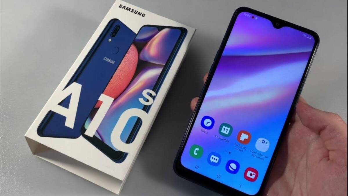 Смартфон Samsung Galaxy A10s в руке рядом с коробкой, Android 11 обновление