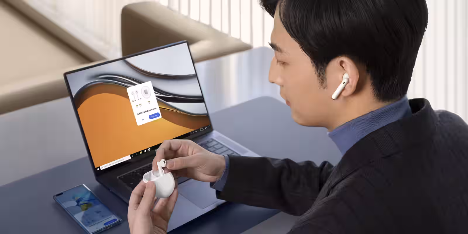 Мужчина с наушниками Huawei FreeBuds 4 использует ноутбук