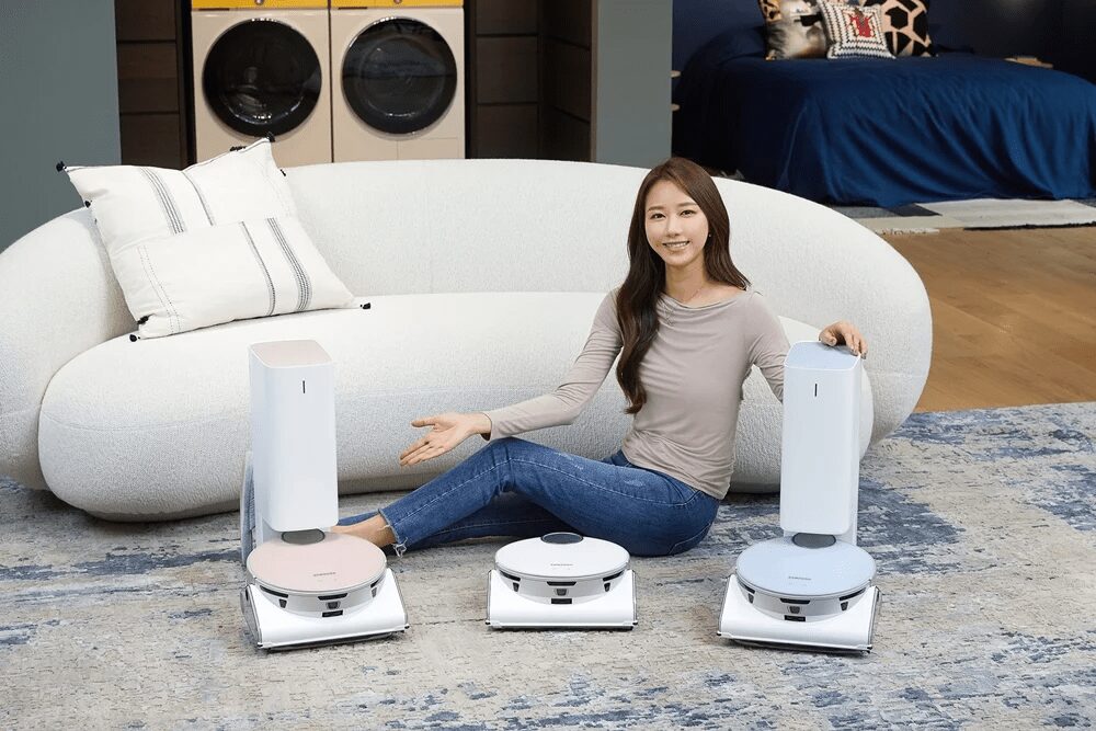 Женщина со смартфонами Samsung Jet Bot AI+ и роботом-пылесосом в гостиной