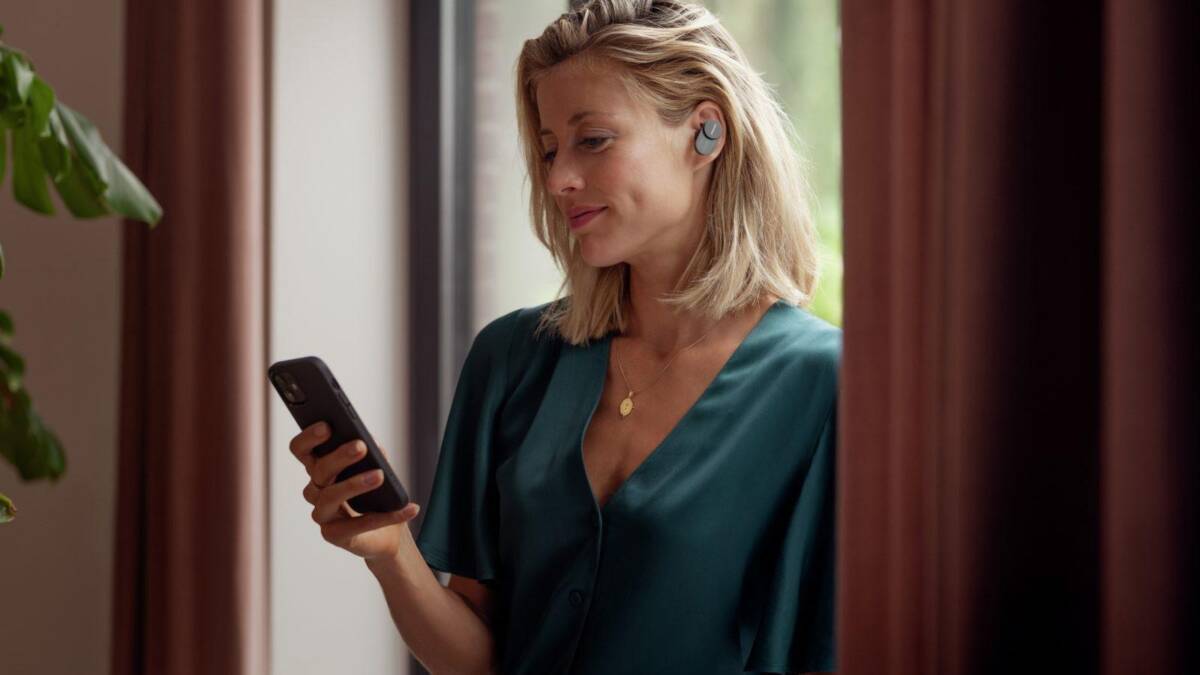 Женщина с наушниками Philips Fidelio T1 держит телефон