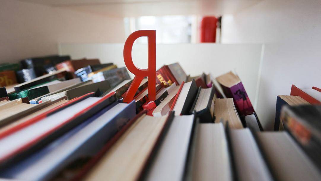 Книжная полка с книгами и заметной закладкой «Яндекс» среди изданий
